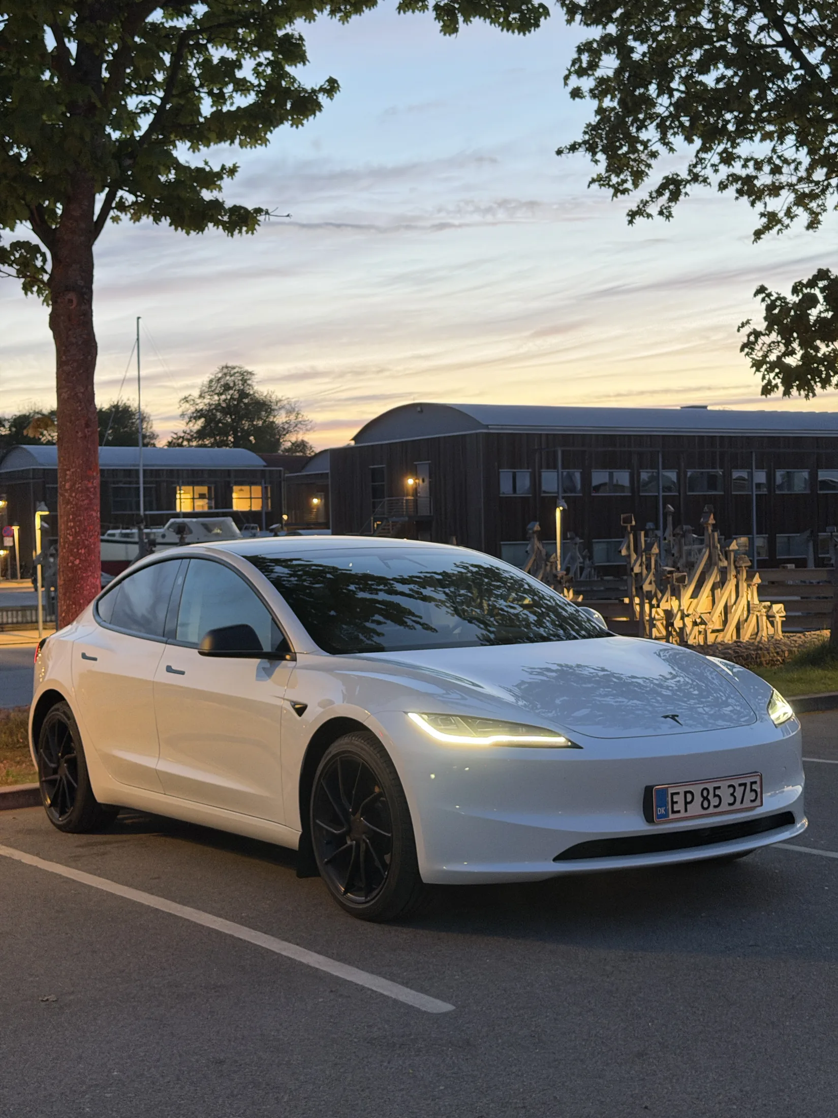 Hvid Tesla foran bygning ved aftenlys
