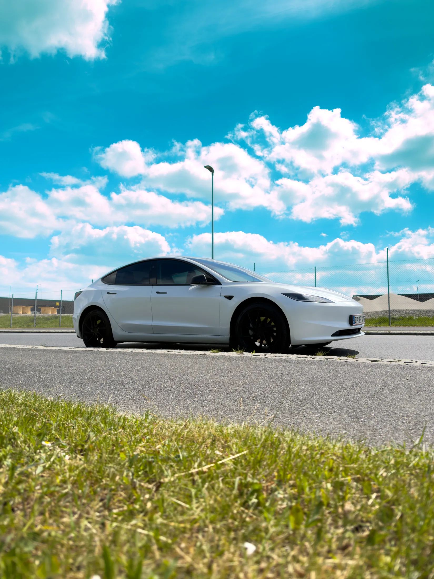 Hvid Tesla set fra lav vinkel med blå himmel